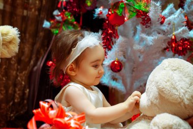 Genç kız beyaz Noel tre altında onun oyuncak ayı ile oynarken