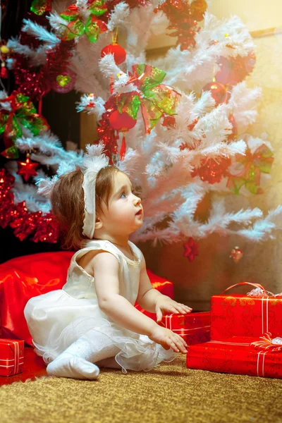 Mała dziewczynka siedzieć pod choinkę z dużą ilością prezent — Zdjęcie stockowe