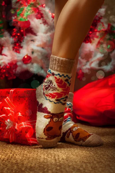 Gambe femminili in calzini divertenti con un sacco di regali di Natale — Foto Stock