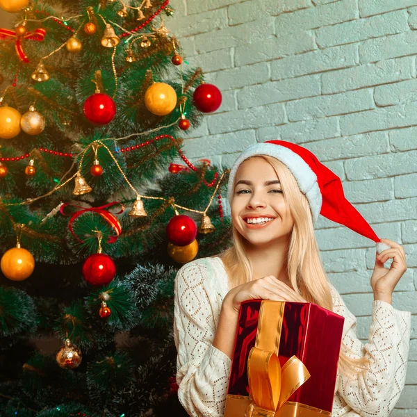 Junge schöne blonde Frau in der Nähe von Weihnachtsbaum mit Geschenk — Stockfoto