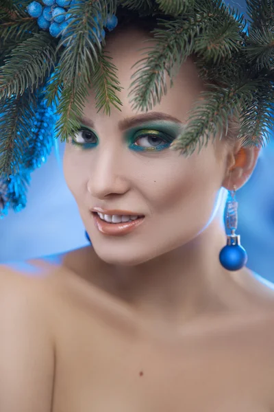 Atemberaubendes junges Mädchen mit Weihnachtsbaumkranz auf dem Kopf schaut auf die Kamera — Stockfoto