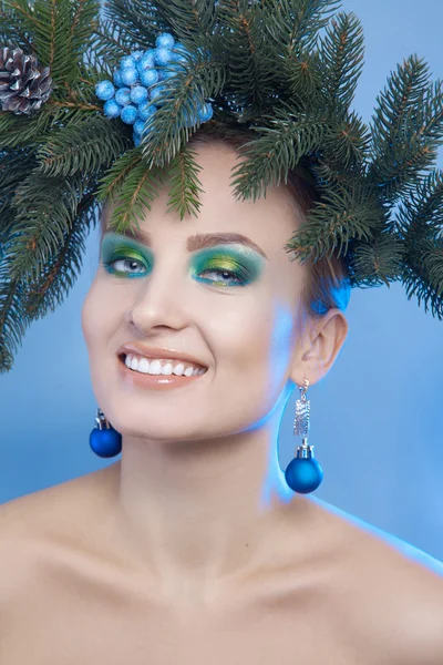 Lustiges Mädchen mit Weihnachtsbaumkranz auf dem Kopf lächelt in die Kamera — Stockfoto