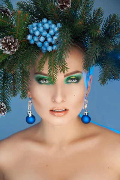 Ernstige jonge vrouw met mooie make-up en xmas boom-krans op hea — Stockfoto