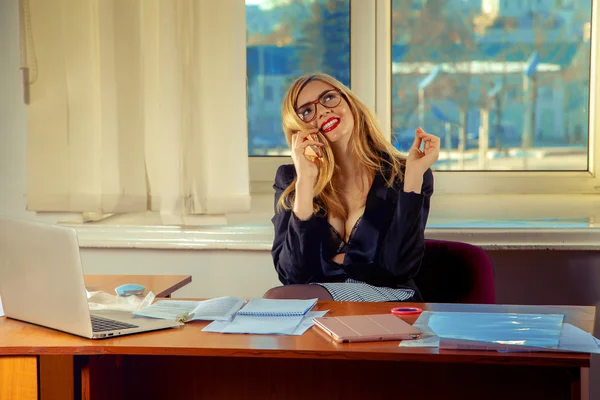 Retrato de una bonita secretaria sentada en su escritorio y sonriendo — Foto de Stock