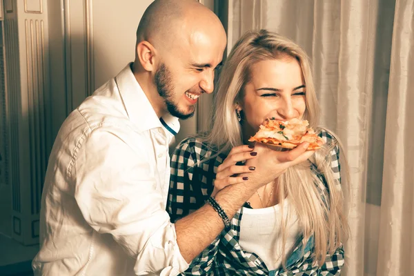 Веселая влюбленная пара веселится с пиццей на вечеринке — стоковое фото