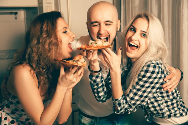 Three people having fun and eating pizza at a party