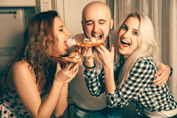 Tres personas divirtiéndose y comiendo pizza en una fiesta — Foto de Stock