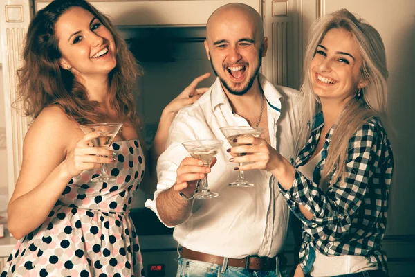 Two girls having fun with a guy at a party with a glass of marti — Stock fotografie