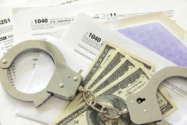 Tax papers with dollar bills and handcuffs