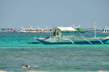 Boracay, Filipinler - 30 Ocak 2020: Gündüz vakti Boracay adasının boş beyaz plajı. Koronavirüs yüzünden Çinli turist yok. Denizdeki tekneler turist taşır.