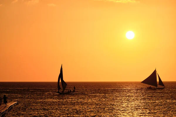 ボラカイ島の夕日 夕日を背景に海に観光客とセーリングや他の伝統的なボート — ストック写真