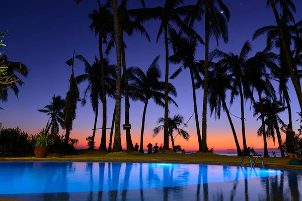 The pool is illuminated at night against the background of the sunset night sky. Diniwid beach during sunset.