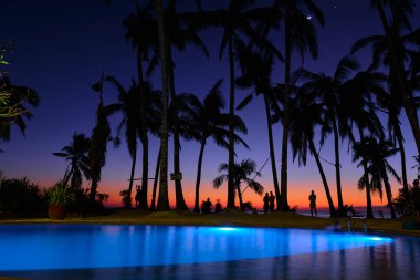 Boracay, Filipinler - 27 Ocak 2020: Havuz gece karanlığında gün batımı gökyüzünün arka planına karşı aydınlatılır. Gün batımında Diniwid plajı.