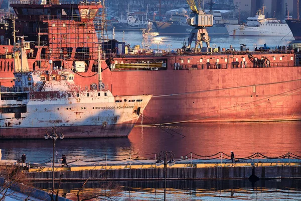 Vladivostok, Russland - Dec 26, 2020: Evening view of the bridge in the Golden Swarm Bay. Gullhornbukta om vinteren. Skipet er under reparasjon i havnen. – stockfoto