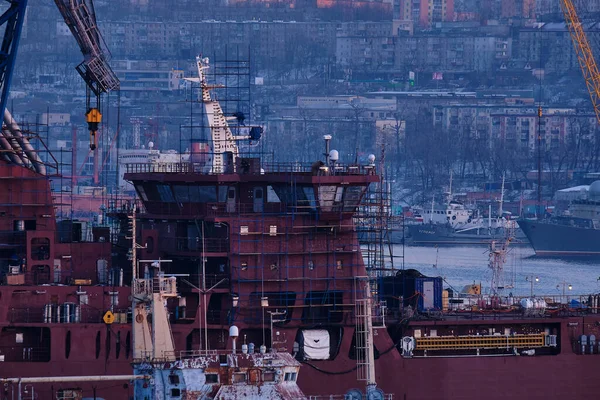 Vladivostok, Rusia - 26 de diciembre de 2020: Vista nocturna del puente en la bahía del enjambre de oro. La bahía del cuerno de oro en invierno. El barco está siendo reparado en el puerto. — Foto de Stock