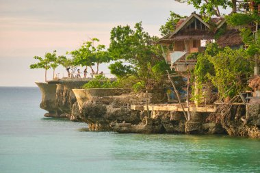Boracay adasında gün batımı. Yelkencilik ve turistlerle dolu diğer geleneksel tekneler batan güneşin arka planında
