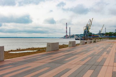 Bahar Parkı parlak güneş tarafından aydınlatılır. Büyük ve güçlü bir nehrin manzarası. Parlak mavi gökyüzünde Güzel beyaz bulutlar.