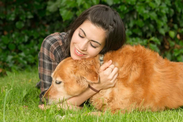 Morena mujer alabando a su perro Golden Retriever canino — Foto de Stock