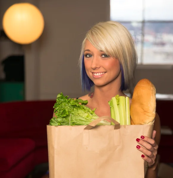 Attraktive Hausfrau stellt Einkaufstasche auf die Theke — Stockfoto