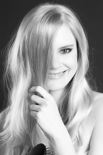 Gyönyörű mosolygós szőke nő ápolás kefével a haját — Stock Fotó