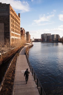 Adamın biri Boardwalk şehir Milwaukee Wisconsin River yürüyüş girer 