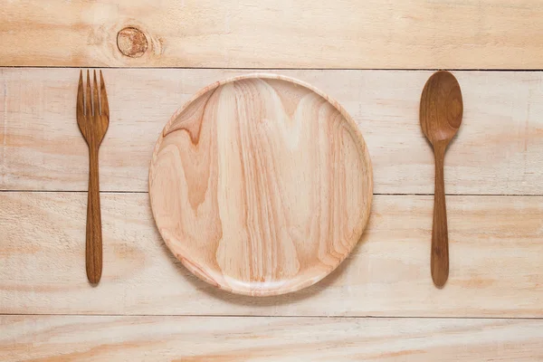 Κουτάλι πηρούνι και πιάτο ξύλου για ξύλινο τραπέζι. — Φωτογραφία Αρχείου