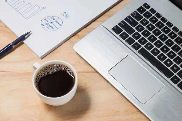笔记本电脑和咖啡的杯，木制的桌子上的业务计划 — 图库照片