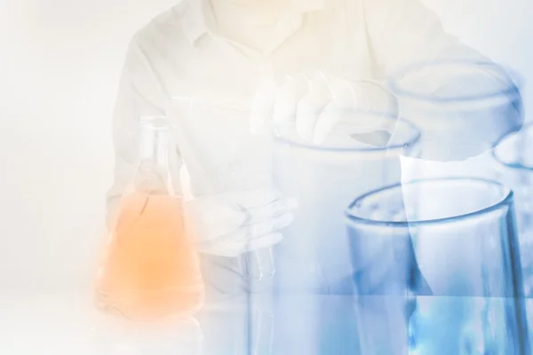 Пробирки в руке ученого с залить химикаты в колбу — стоковое фото