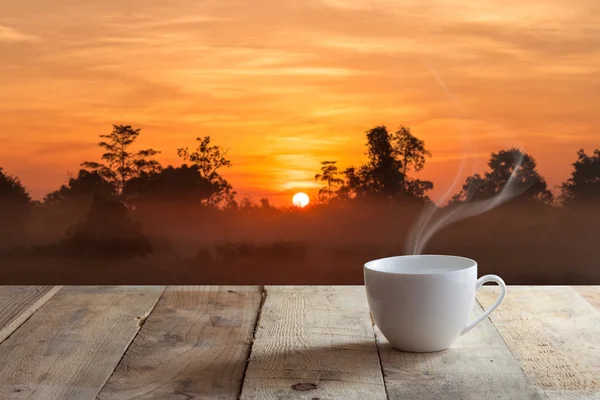 Taza de café negro sobre mesa de madera y puesta del sol — Foto de Stock