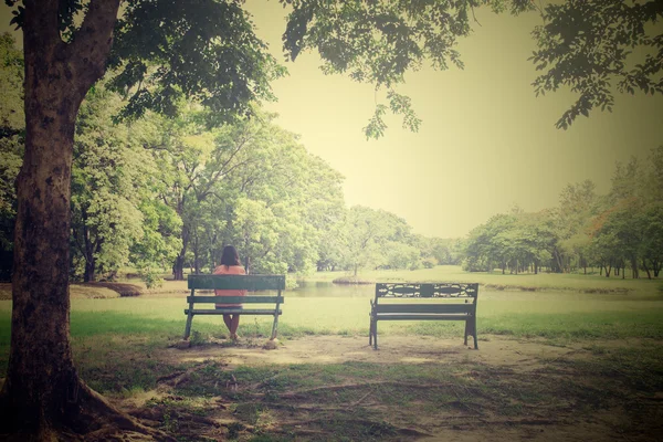 Asian young lonely woman on bench in park,in vintage style — Stock Photo, Image