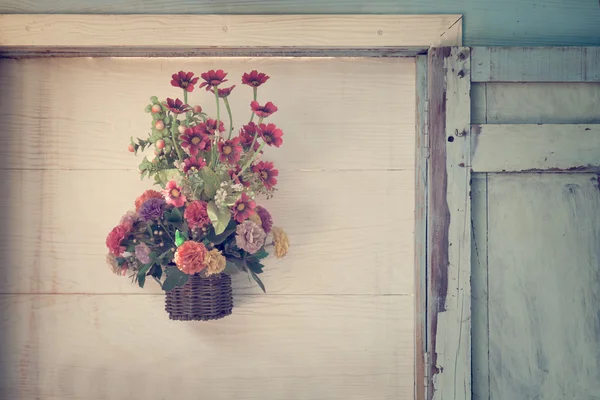 Konstgjorda blommor på trä vägg — Stockfoto