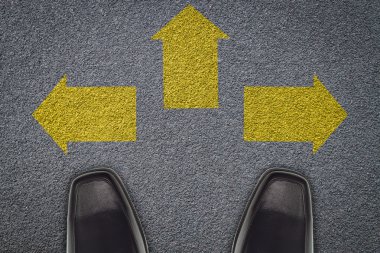 asfalt yol üzerinde üç ok önünde duran işadamı,