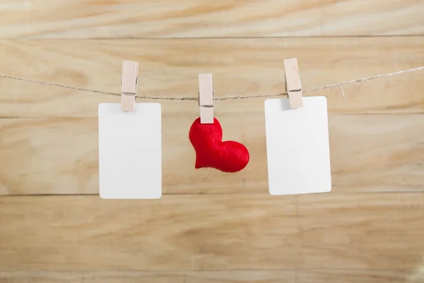 Nota em branco e corações vermelhos pendurados na corda com fundo de madeira — Fotografia de Stock