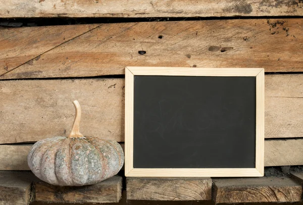 Blackboard and pumpkin on wooden background — Stock Photo, Image