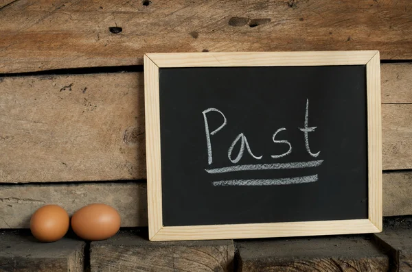 Blackboard writing and eggs on wooden background — Stock Photo, Image