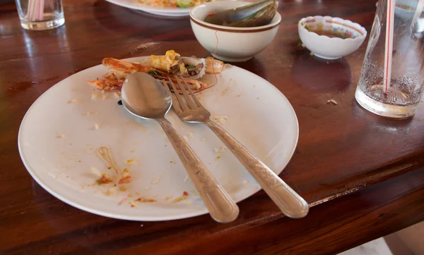 Белая тарелка с крошками, использованная вилка и использованная ложка Стоковое Изображение