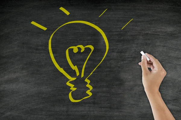 Hand drawing light bulb on blackboard — Stock Photo, Image