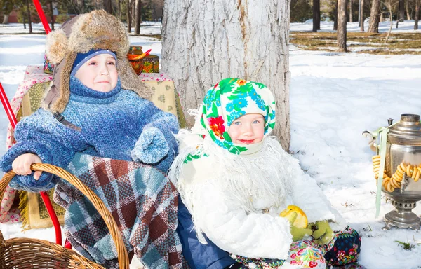 Children in Russian pavloposadskie scarf on head with floral print on snow.  Russian style on a background of samovar and with  bagels — Stock Photo, Image