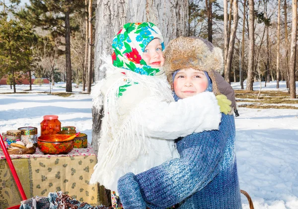 Děti v ruské pavloposadskie šátek na hlavu s květinovým potiskem na sněhu. Ruský styl na pozadí samovar a bagely — Stock fotografie