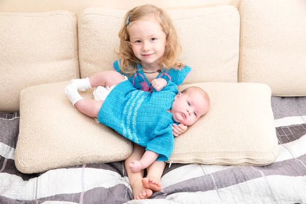 Två systrar. Äldre syster kid kramar sin nyfödda lillasyster. Söta barn flickor liggande på sängen hemma. — Stockfoto