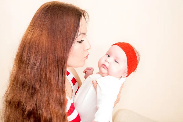 Joyeux maman et fille nouveau-né câlins à la maison. Le concept enfance et famille. Belle mère et son bébé — Photo