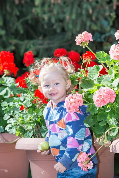 Little child girl in park near flowers — Stock Photo, Image