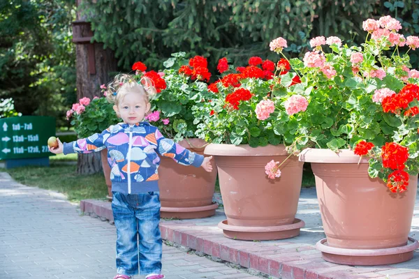 Meisje kind in park in de buurt van bloemen — Stockfoto