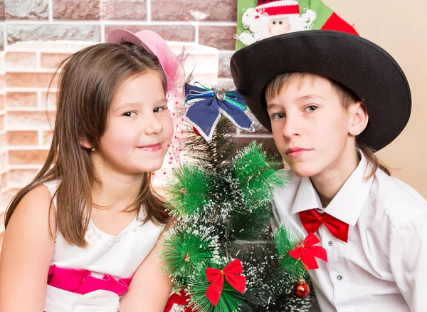 Meneer jongen en meisje in bal jurk bij open haard. Kerstmis en Nieuwjaar — Stockfoto