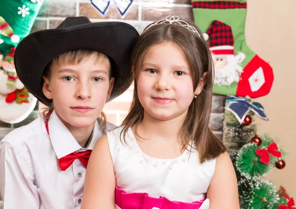 Meneer jongen en meisje in bal jurk bij open haard. Kerstmis en Nieuwjaar — Stockfoto