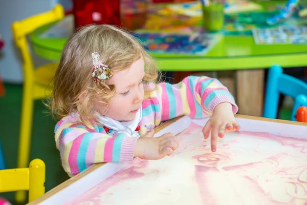 Cute child girl drawing on sand — Stock Photo, Image