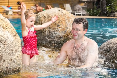 Tropikal tatil Havuzda yüzmek için yürümeye başlayan çocuk kızı öğretim etkin baba. Yaz tatillerini ve spor kavram