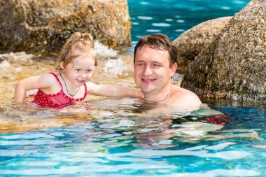 Tropikal tatil Havuzda yüzmek için yürümeye başlayan çocuk kızı öğretim etkin baba. Yaz tatillerini ve spor kavram