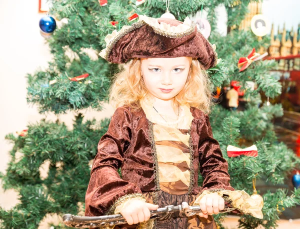 Kisgyermek lány öltözött kalóz Halloween háttérben a karácsonyfa. Kölyök farsangi jelmez karácsonyra — Stock Fotó