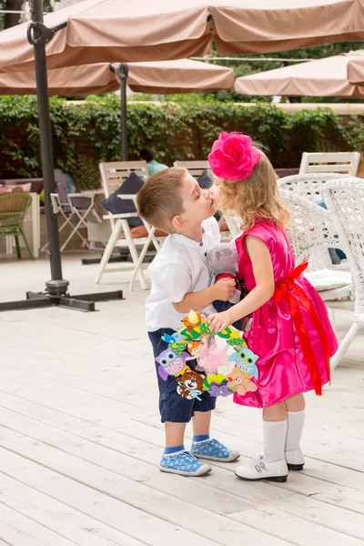 Il bambino ragazzo regala fiori e bacia la bambina il giorno del compleanno. Piccola ragazza adorabile che festeggia 3 anni di compleanno. Infanzia. . — Foto Stock